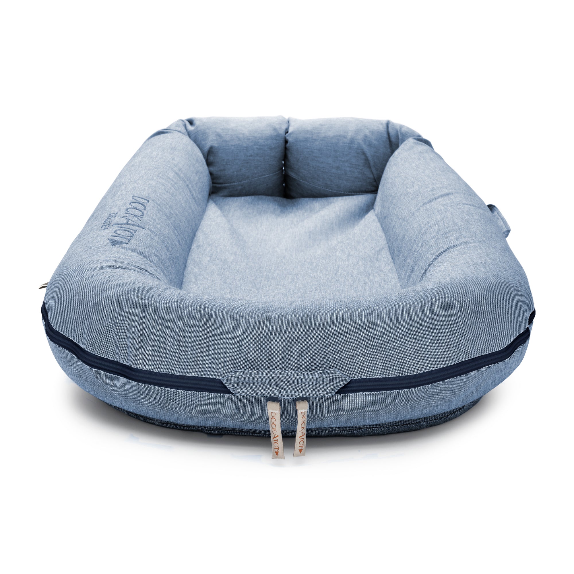 A square-shaped, denim-blue dog bed with raised padded edges and a darker blue trim. The bed features a subtle centered DockATot logo and conforms to the Oeko-Tex Standard 100, ensuring it is LAST CHANCE: Deluxe+ Dock - Indigo Chambray.