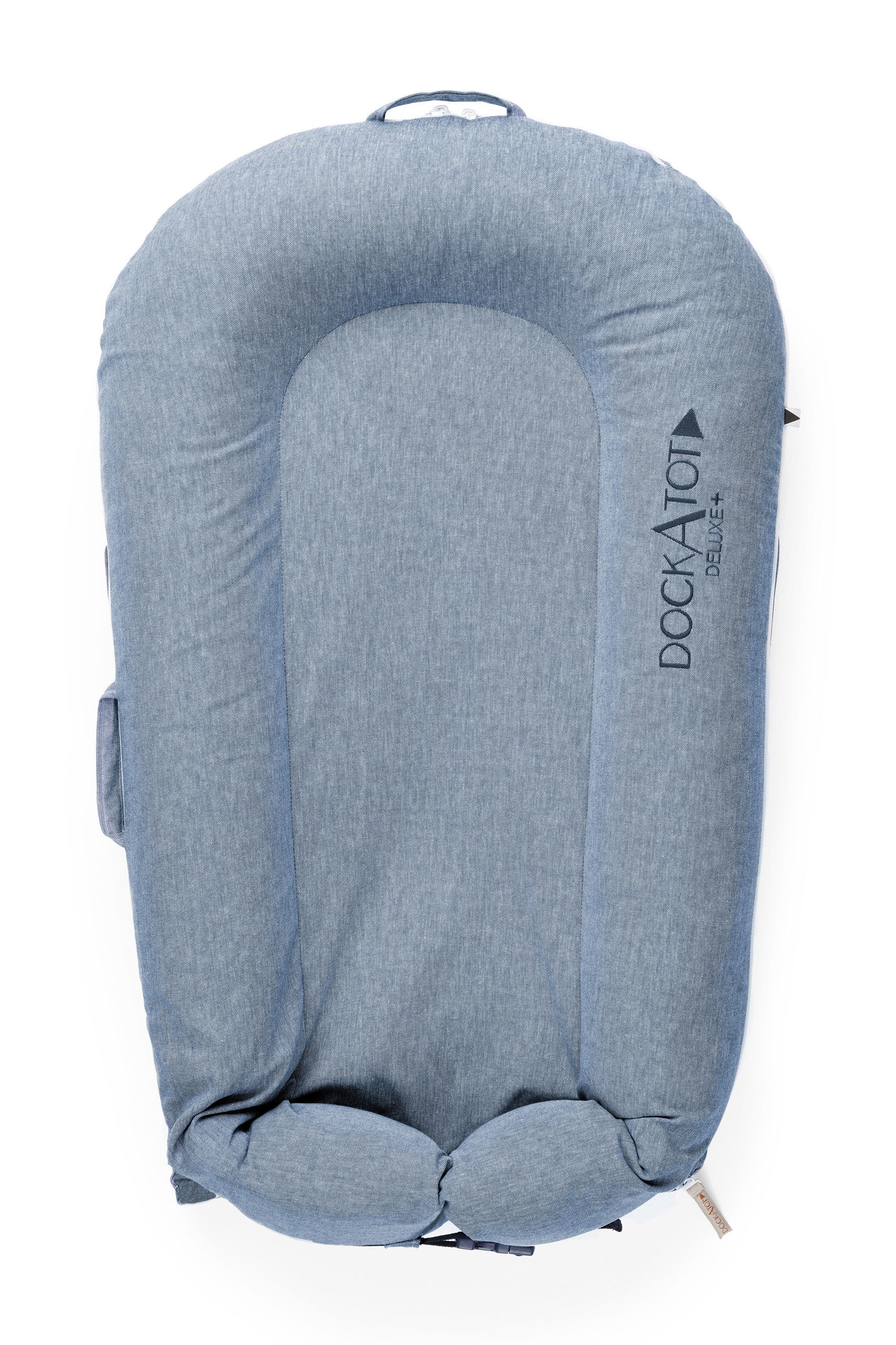 A blue DockATot LAST CHANCE: Deluxe+ Dock - Indigo Chambray baby lounger isolated on a white background. The lounger has a cushioned, oval shape with side handles and prominently displays the "DockATot" logo.